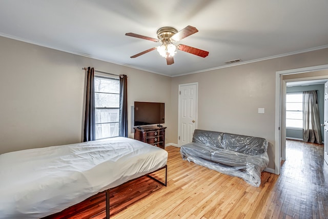 bedroom with ceiling fan, ornamental molding, wood-type flooring, and multiple windows