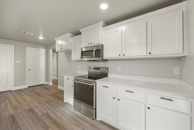 kitchen with stainless steel appliances, light stone countertops, light hardwood / wood-style flooring, and white cabinets