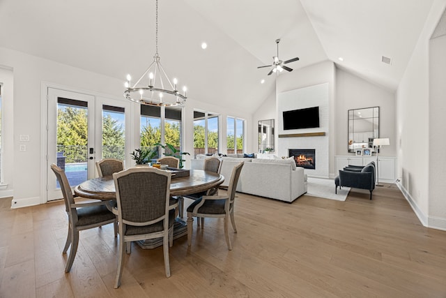 dining room featuring ceiling fan with notable chandelier, high vaulted ceiling, and light hardwood / wood-style floors