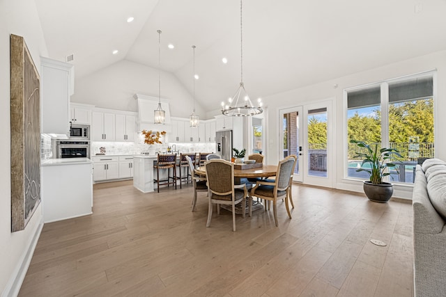 dining area featuring french doors, high vaulted ceiling, and light hardwood / wood-style flooring