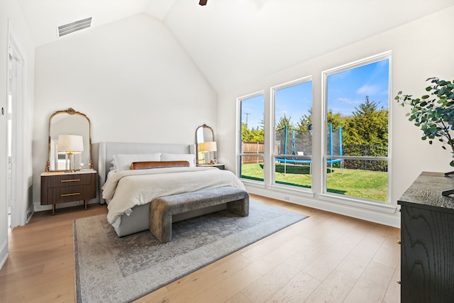 bedroom with high vaulted ceiling, multiple windows, and light wood-type flooring