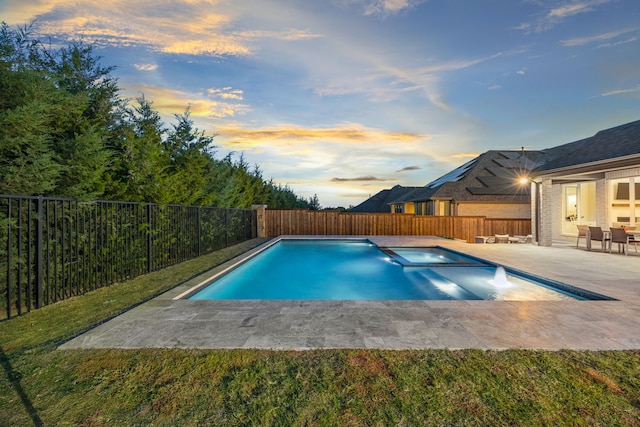 pool at dusk featuring an in ground hot tub and a patio area