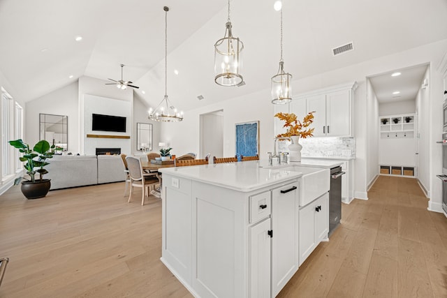 kitchen with light hardwood / wood-style flooring, an island with sink, hanging light fixtures, and white cabinets