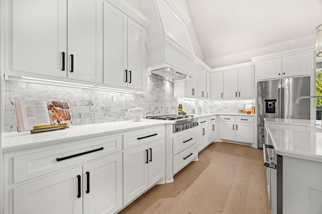 kitchen with vaulted ceiling, appliances with stainless steel finishes, and white cabinets