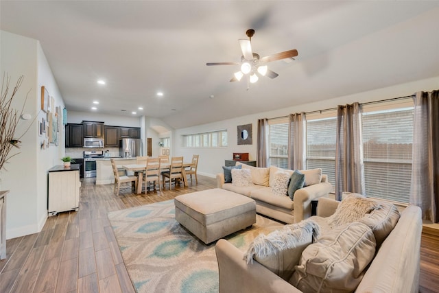 living room with ceiling fan, lofted ceiling, and light hardwood / wood-style floors