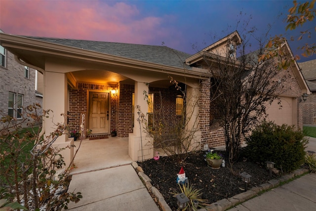 exterior entry at dusk with a garage and covered porch