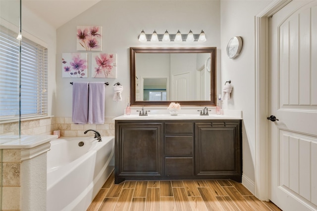 bathroom with vaulted ceiling, vanity, and a bathing tub