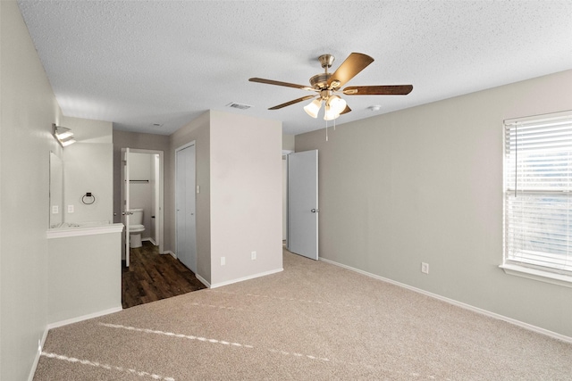 spare room with dark colored carpet, ceiling fan, and a textured ceiling