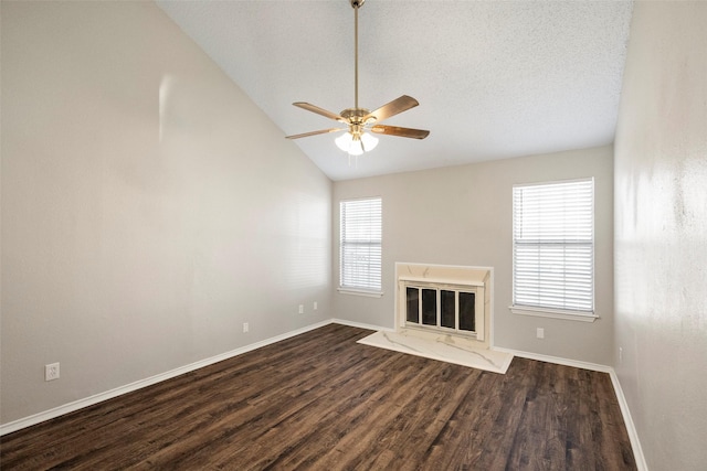 unfurnished living room featuring vaulted ceiling, a textured ceiling, dark hardwood / wood-style floors, ceiling fan, and a premium fireplace