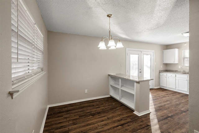 unfurnished dining area featuring dark hardwood / wood-style floors, a wealth of natural light, and a chandelier