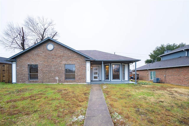 rear view of property featuring central air condition unit and a lawn