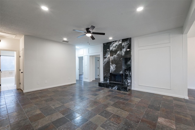 unfurnished living room with a textured ceiling, a premium fireplace, and ceiling fan