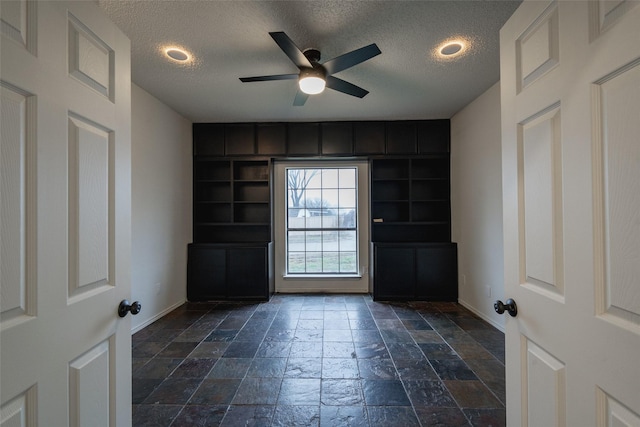 interior space with ceiling fan and a textured ceiling