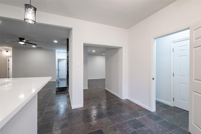 interior space with ceiling fan, hanging light fixtures, and a textured ceiling