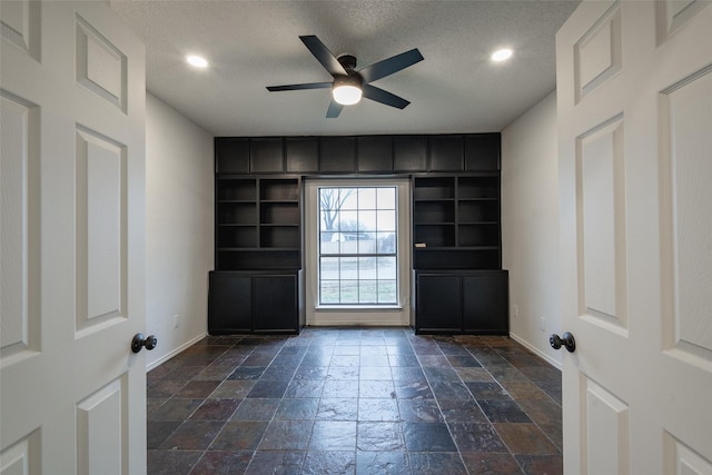 interior space with ceiling fan and a textured ceiling