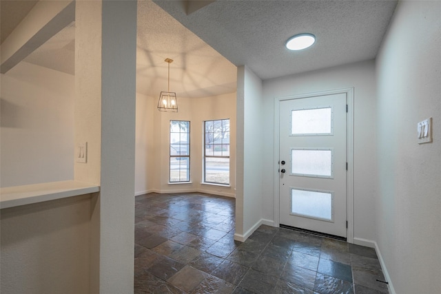 entryway with a textured ceiling and a notable chandelier