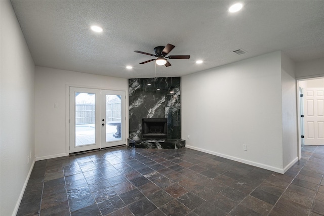 unfurnished living room featuring ceiling fan, a textured ceiling, a high end fireplace, and french doors