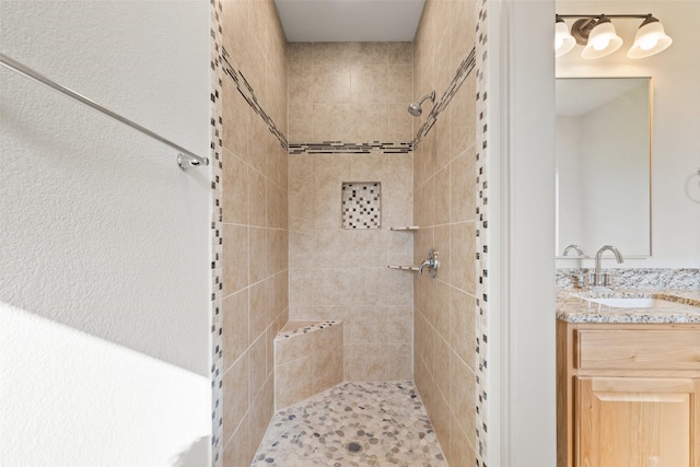 full bath with a tile shower and vanity