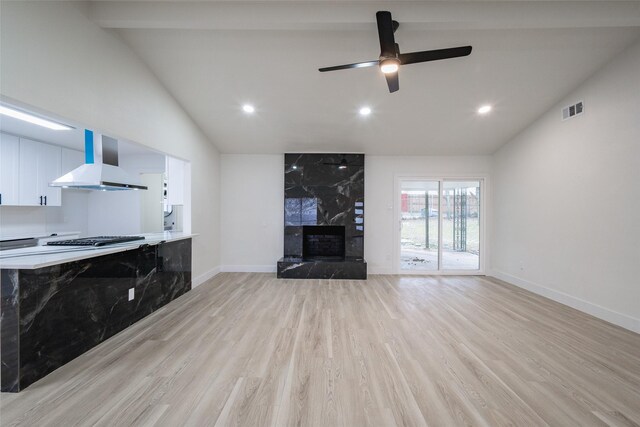 unfurnished living room with light hardwood / wood-style flooring, vaulted ceiling with beams, a fireplace, and ceiling fan