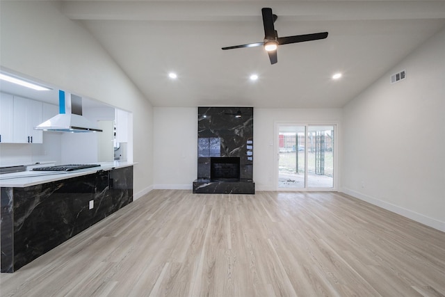 living room with ceiling fan, lofted ceiling, a premium fireplace, and light wood-type flooring