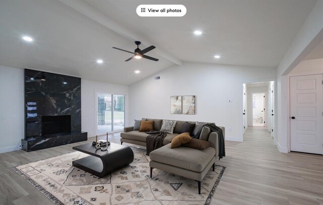 unfurnished living room with a high end fireplace, light hardwood / wood-style floors, ceiling fan, and vaulted ceiling