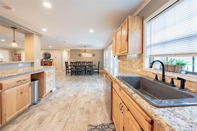 kitchen featuring light brown cabinetry, sink, hanging light fixtures, and a wealth of natural light