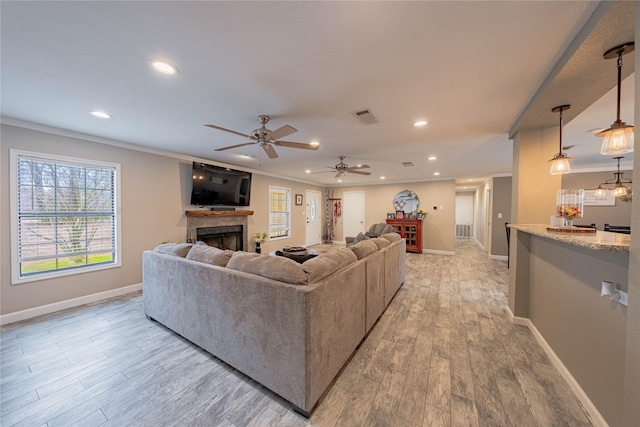 living room with ornamental molding, ceiling fan, and light wood-type flooring