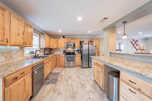 kitchen featuring sink, light stone counters, light wood-type flooring, appliances with stainless steel finishes, and pendant lighting