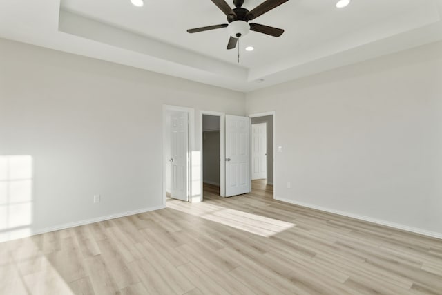 unfurnished room featuring a tray ceiling, light hardwood / wood-style flooring, and ceiling fan