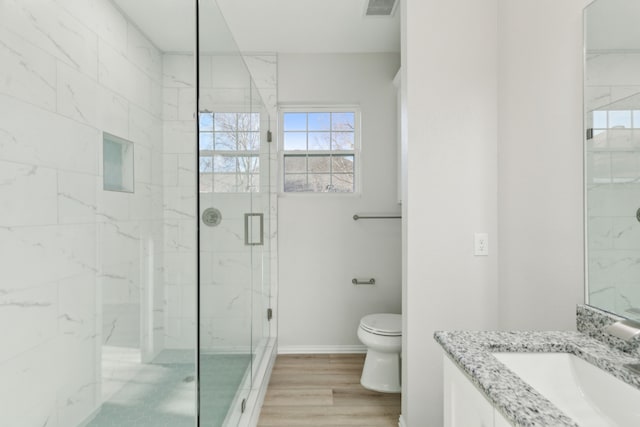 bathroom featuring vanity, hardwood / wood-style floors, a shower with shower door, and toilet