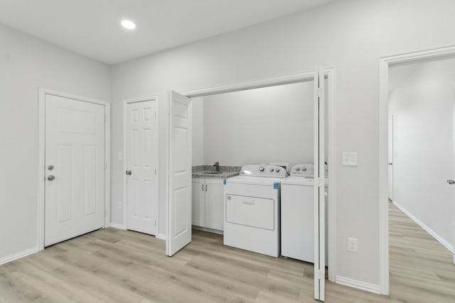 clothes washing area featuring washing machine and clothes dryer, sink, and light hardwood / wood-style floors