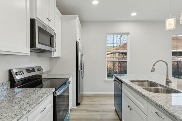 kitchen with sink, white cabinetry, light stone counters, hanging light fixtures, and stainless steel appliances