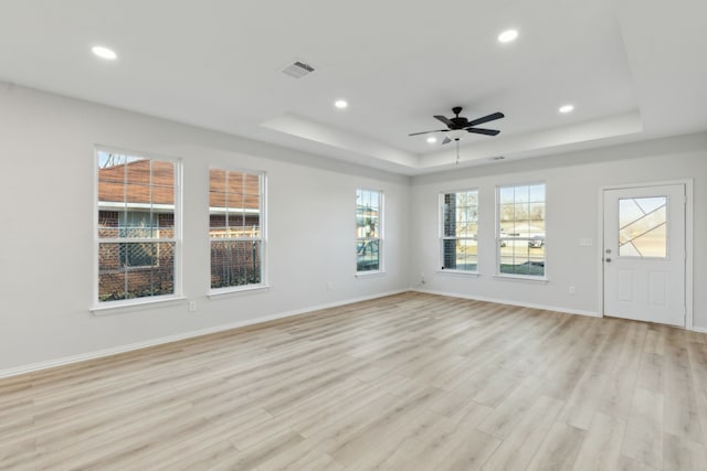 unfurnished living room featuring ceiling fan, a raised ceiling, and light wood-type flooring