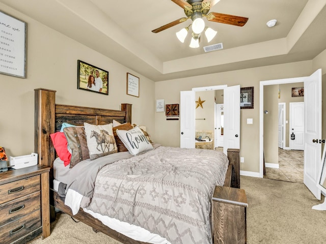 carpeted bedroom featuring ceiling fan and a raised ceiling