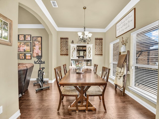 dining space featuring dark hardwood / wood-style flooring, ornamental molding, and a chandelier