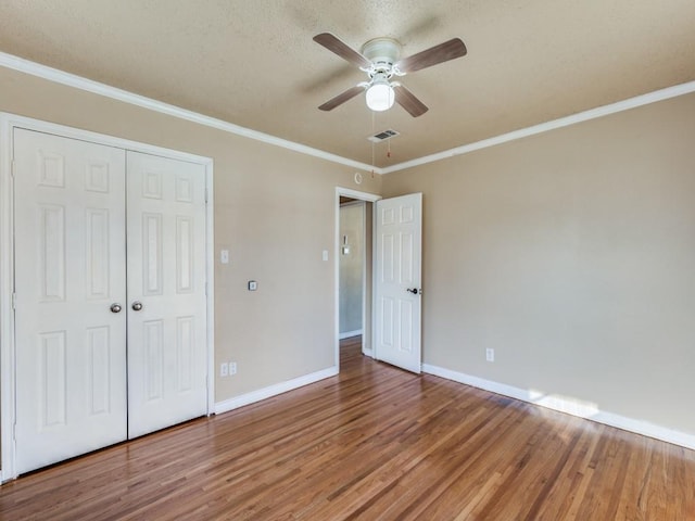 unfurnished bedroom featuring crown molding, hardwood / wood-style floors, ceiling fan, and a closet