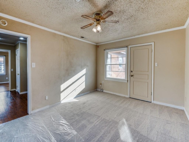 carpeted spare room featuring ceiling fan, ornamental molding, and a textured ceiling