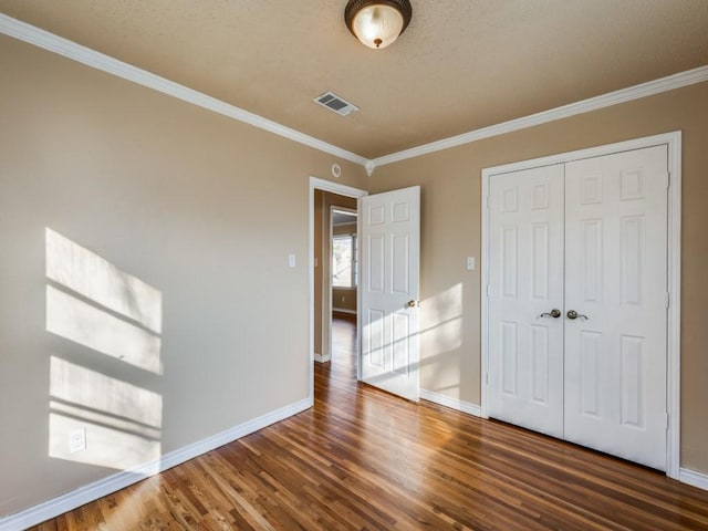 unfurnished bedroom with crown molding, dark hardwood / wood-style floors, and a closet