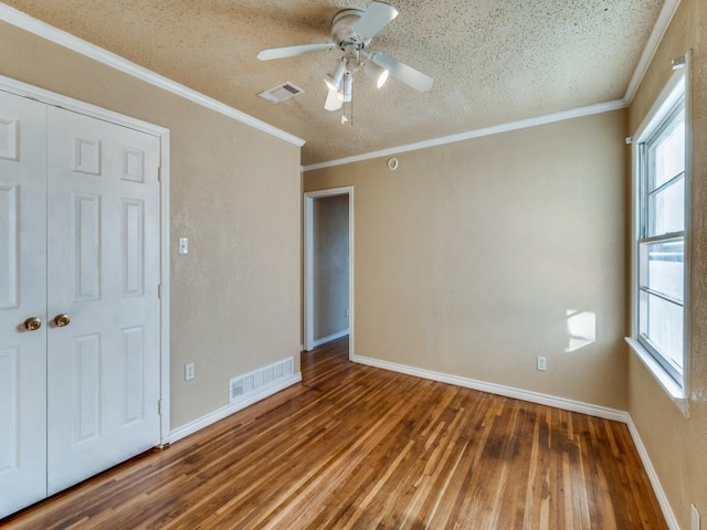 unfurnished bedroom with hardwood / wood-style flooring, crown molding, and multiple windows