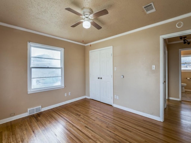 unfurnished bedroom with ceiling fan, hardwood / wood-style floors, ornamental molding, a textured ceiling, and a closet