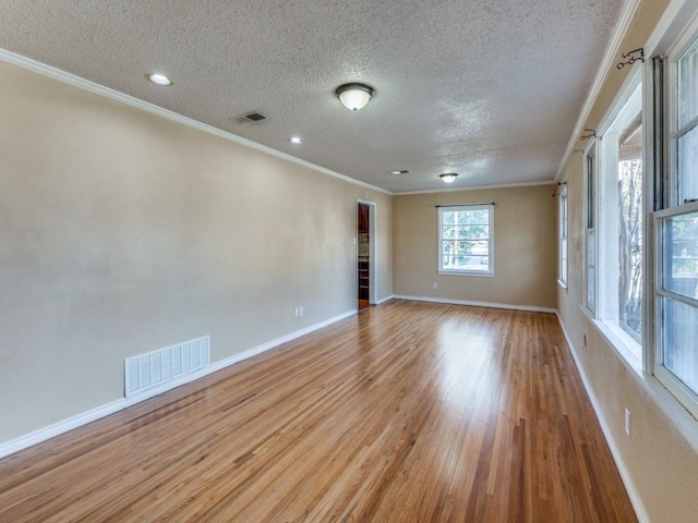 empty room featuring crown molding, light hardwood / wood-style floors, and a textured ceiling