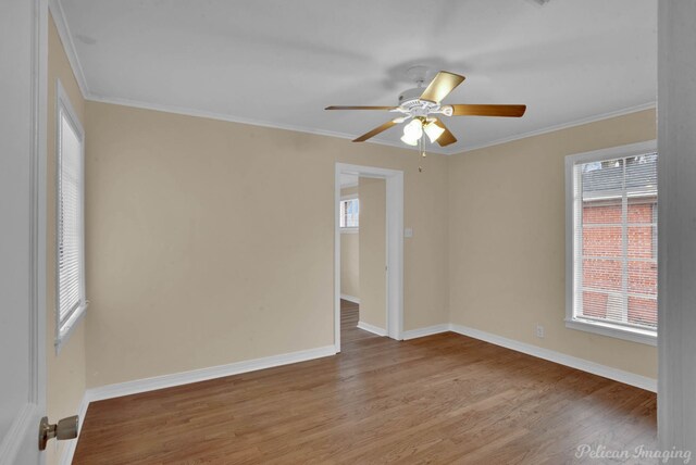 empty room featuring ornamental molding, wood finished floors, and baseboards