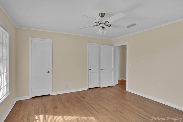 unfurnished bedroom with crown molding, visible vents, a ceiling fan, light wood-type flooring, and baseboards