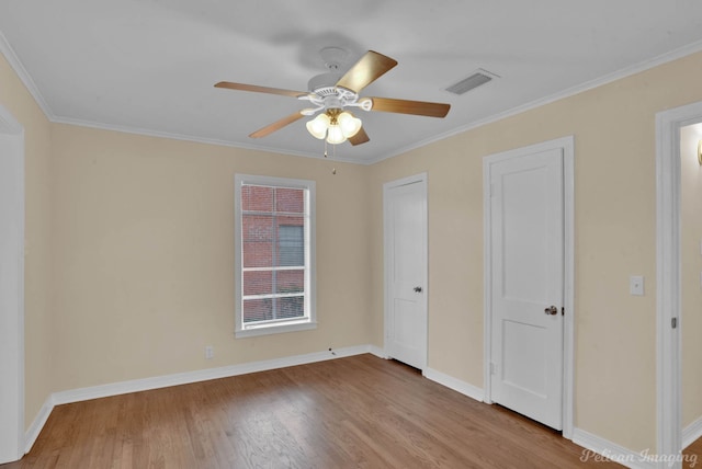 unfurnished bedroom featuring light wood-style floors, baseboards, visible vents, and crown molding