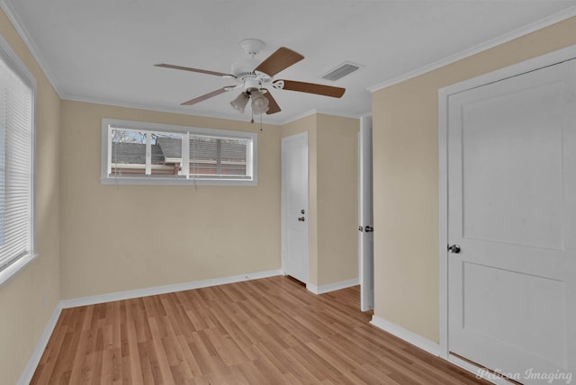 unfurnished room with visible vents, crown molding, light wood-style flooring, and baseboards