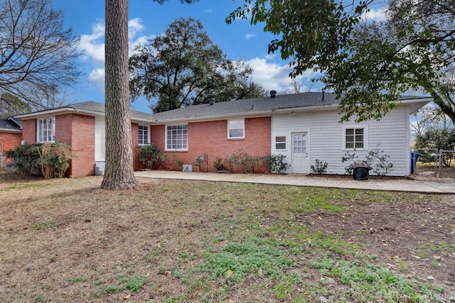 back of property featuring a yard and brick siding