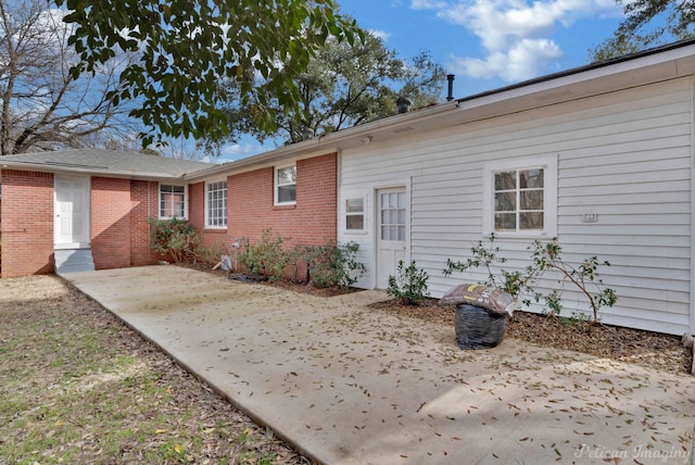 rear view of property with brick siding and a patio area