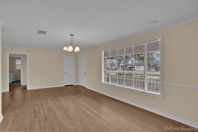 empty room featuring ornamental molding, wood finished floors, and a notable chandelier