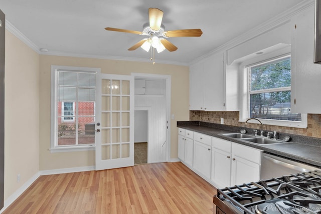 kitchen with white cabinets, dark countertops, a sink, light wood-type flooring, and backsplash