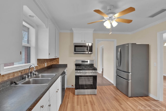 kitchen with visible vents, dark countertops, appliances with stainless steel finishes, white cabinetry, and a sink